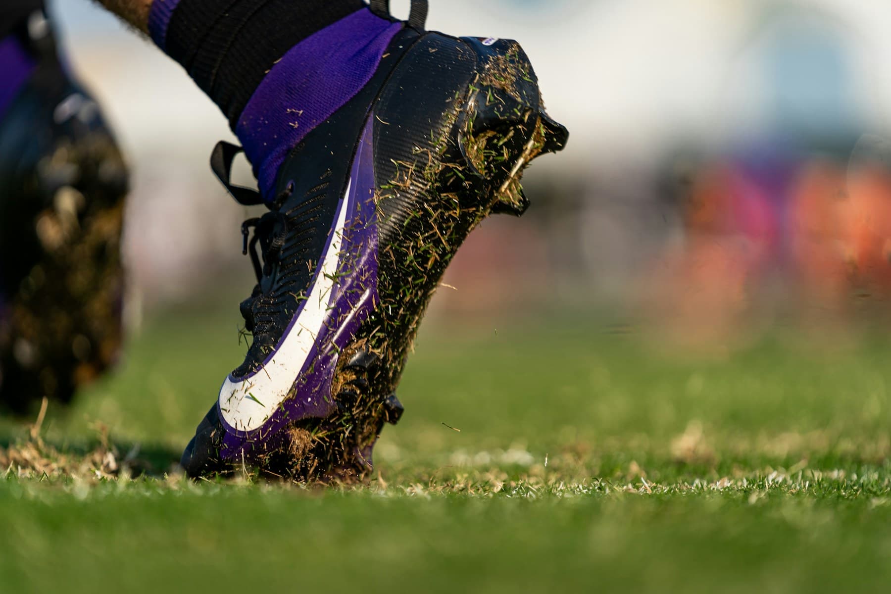 A grass-stained football boot resting on the pitch